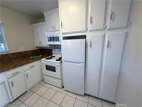 a kitchen with white cabinets and white appliances