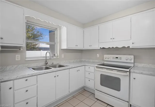 a kitchen with granite countertop white cabinets white appliances and a sink