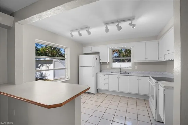 a kitchen with white cabinets and window