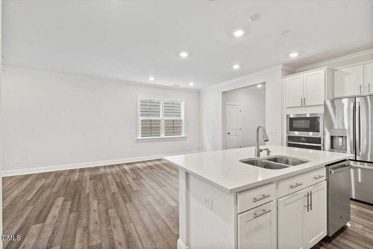 4937 Abundance Avenue Raleigh, NC 27616 - Photo 9 of 36 a kitchen with stainless steel appliances granite countertop a sink dishwasher a refrigerator and white cabinets with wooden floor