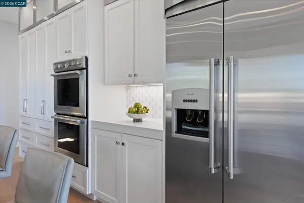 a kitchen with stainless steel appliances a white cabinets and wooden floors