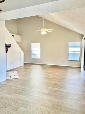 a view of an empty room with window and wooden floor
