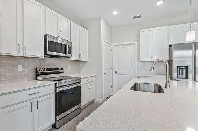 a kitchen with white cabinets and stainless steel appliances