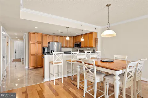 a kitchen with stainless steel appliances kitchen island granite countertop a dining table chairs and white cabinets