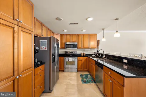 a kitchen with stainless steel appliances granite countertop a sink a stove and refrigerator