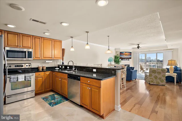 a kitchen with stainless steel appliances granite countertop a stove top oven a sink dishwasher a dining table and chairs with wooden floor