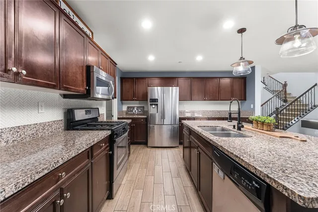 a kitchen with stainless steel appliances granite countertop granite counter tops a stove a sink dishwasher a refrigerator and wooden cabinets