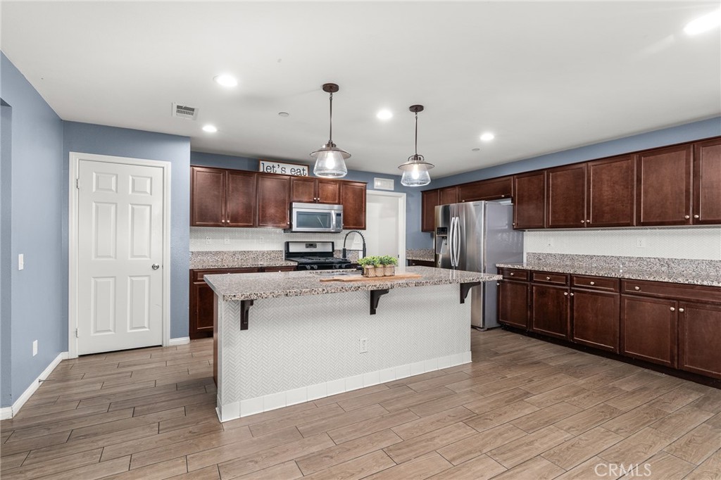 136 Yosemite Avenue Perris, CA 92570 - Photo 6 of 31 a kitchen with stainless steel appliances kitchen island granite countertop a refrigerator a stove top oven and a sink with cabinets