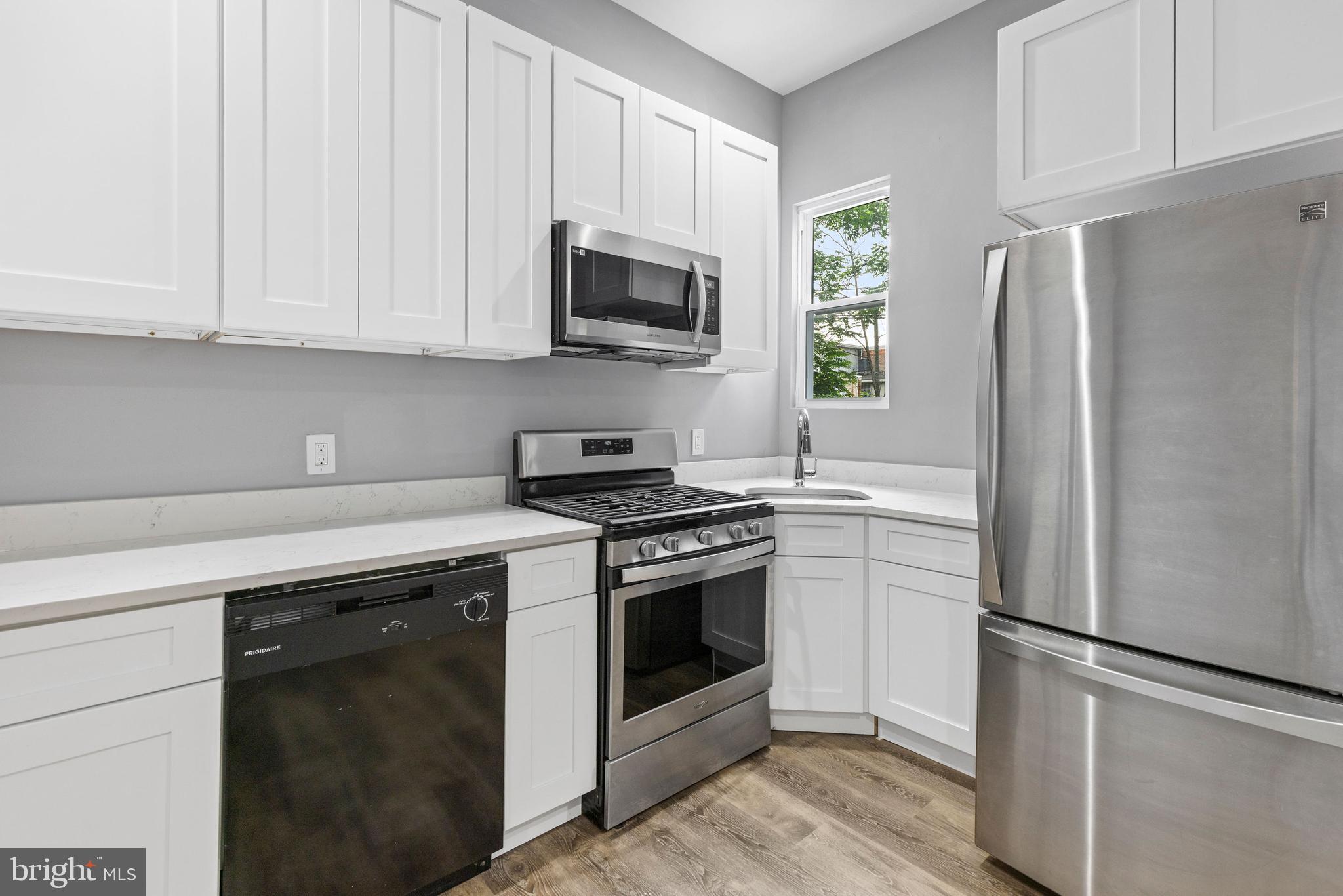 1809 West Lombard Street Baltimore, MD 21223 - Photo 6 of 36 a kitchen with stainless steel appliances granite countertop a refrigerator stove a sink and dishwasher with wooden floor