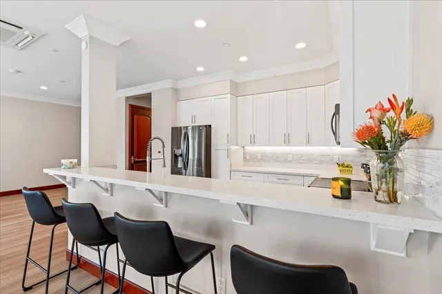 a kitchen with a dining table chairs and white cabinets with wooden floor