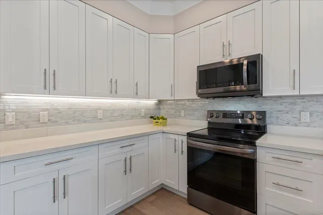 a kitchen with white cabinets and black appliances