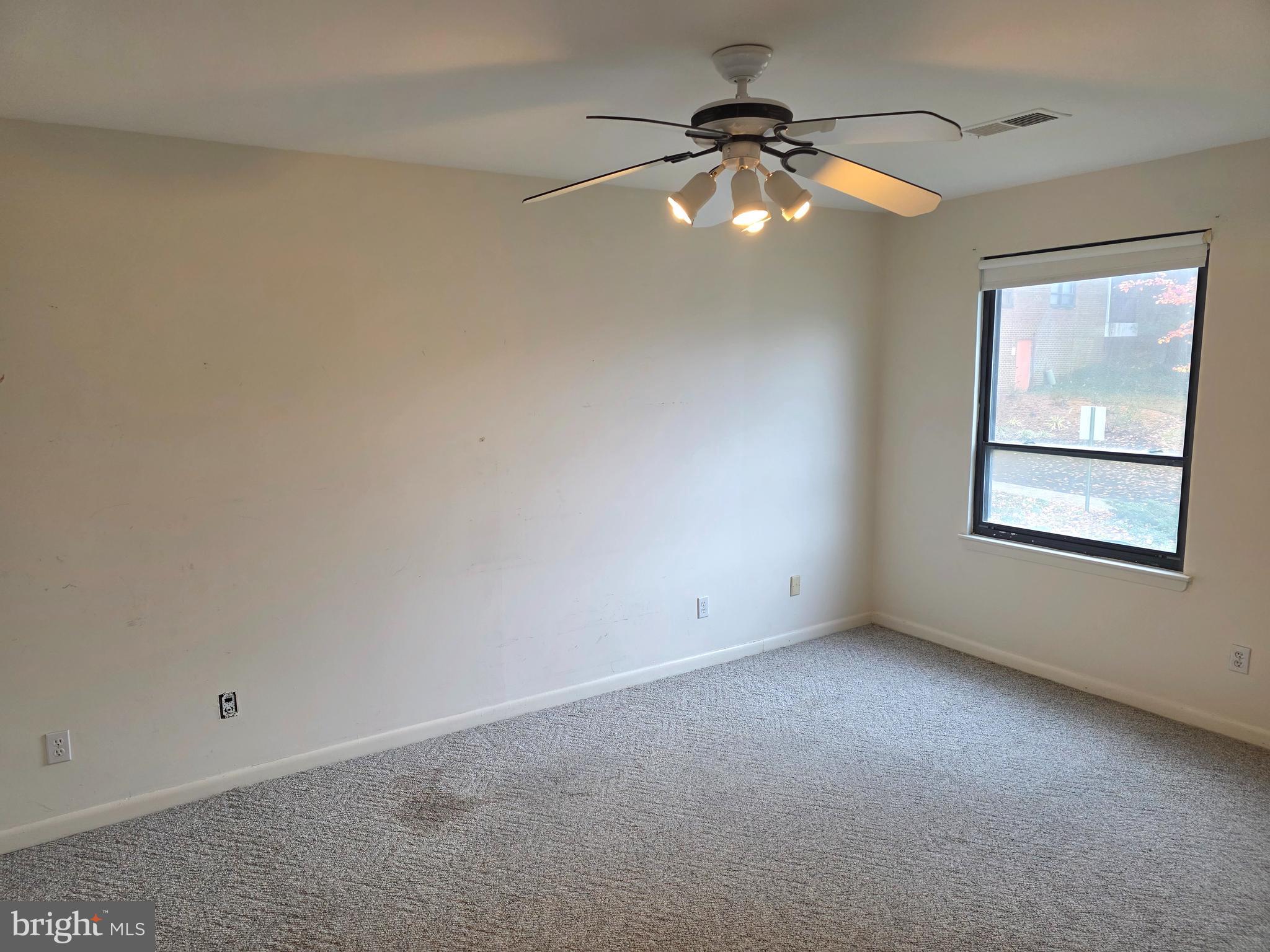6317 Park Heights Avenue, Unit 103 Baltimore, MD 21215 - Photo 3 of 10 an empty room with a chandelier fan and windows