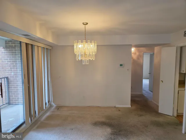 an empty room with chandelier fan and windows