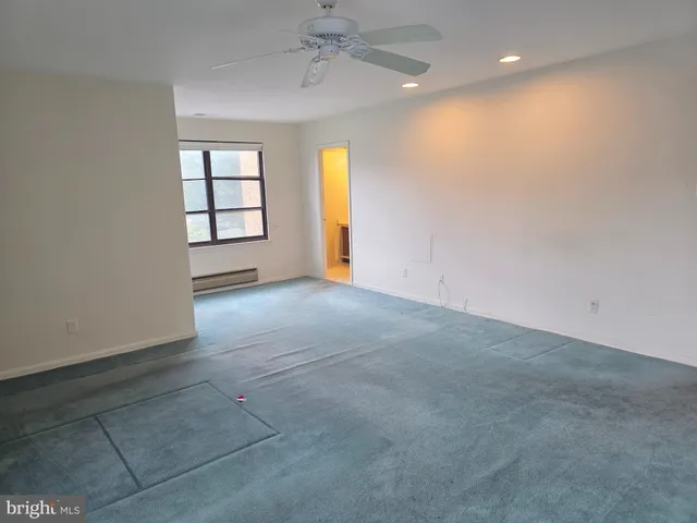 an empty room with windows and fan