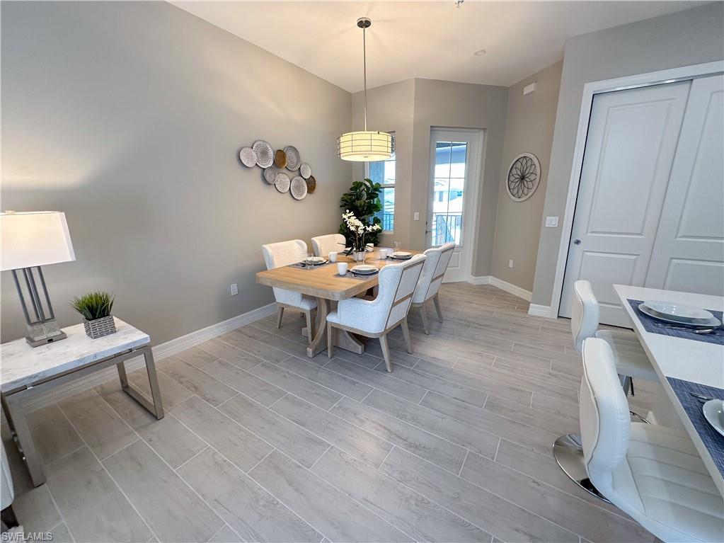 262 Indies Drive East, Unit 201 Naples, FL 34114 - Photo 11 of 45 a living room with a table chairs and a wooden floor