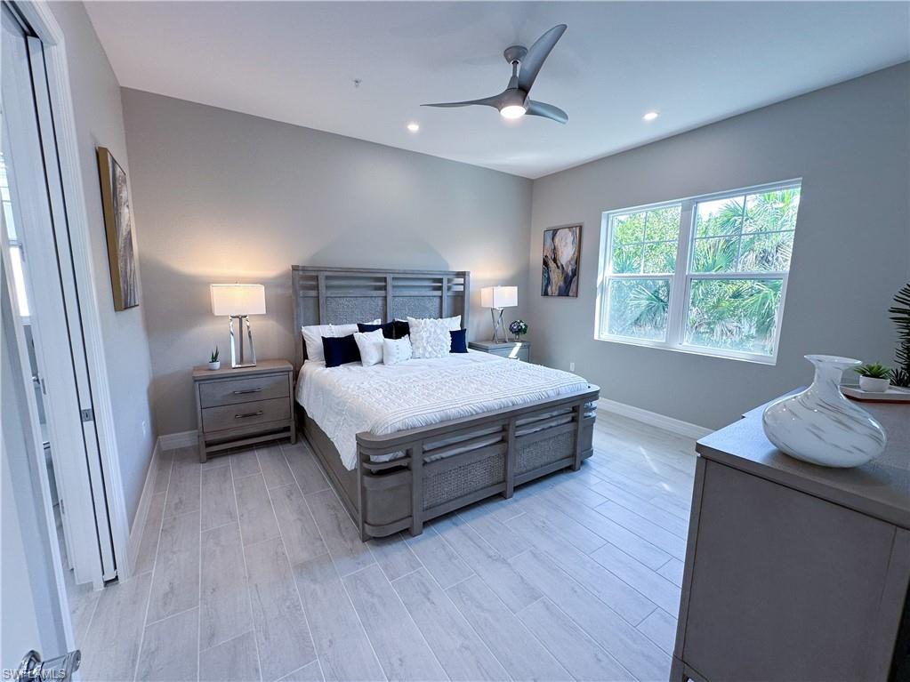 262 Indies Drive East, Unit 201 Naples, FL 34114 - Photo 17 of 45 a bedroom with a bed a couch and a window