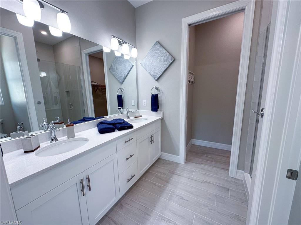 262 Indies Drive East, Unit 201 Naples, FL 34114 - Photo 21 of 45 a bathroom with a double vanity sink and a mirror