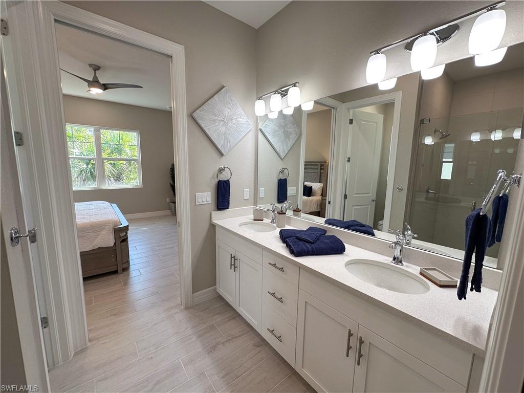 262 Indies Drive East, Unit 201 Naples, FL 34114 - Photo 22 of 45 a en suite bathroom with a double vanity sink and mirror