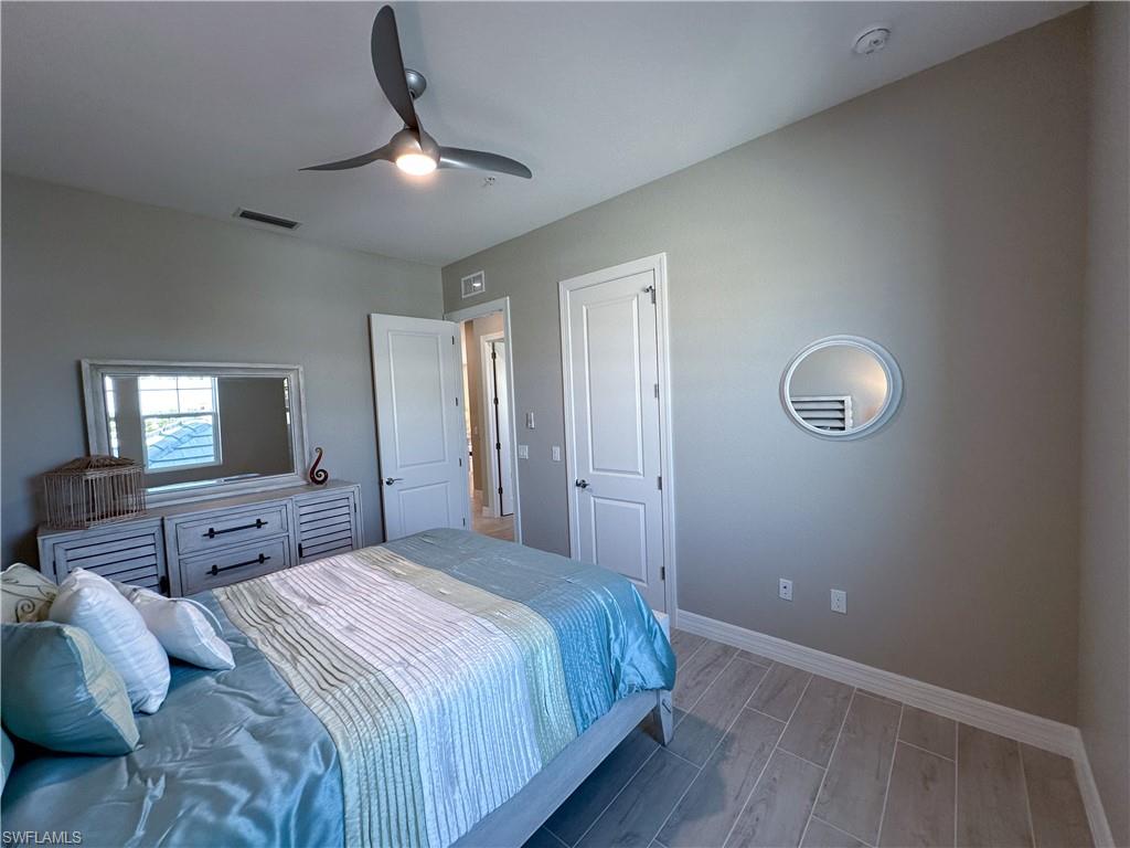 262 Indies Drive East, Unit 201 Naples, FL 34114 - Photo 32 of 45 a bedroom with a large bed and a chandelier
