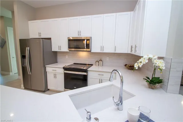 a kitchen with stainless steel appliances a sink a microwave a refrigerator and cabinets