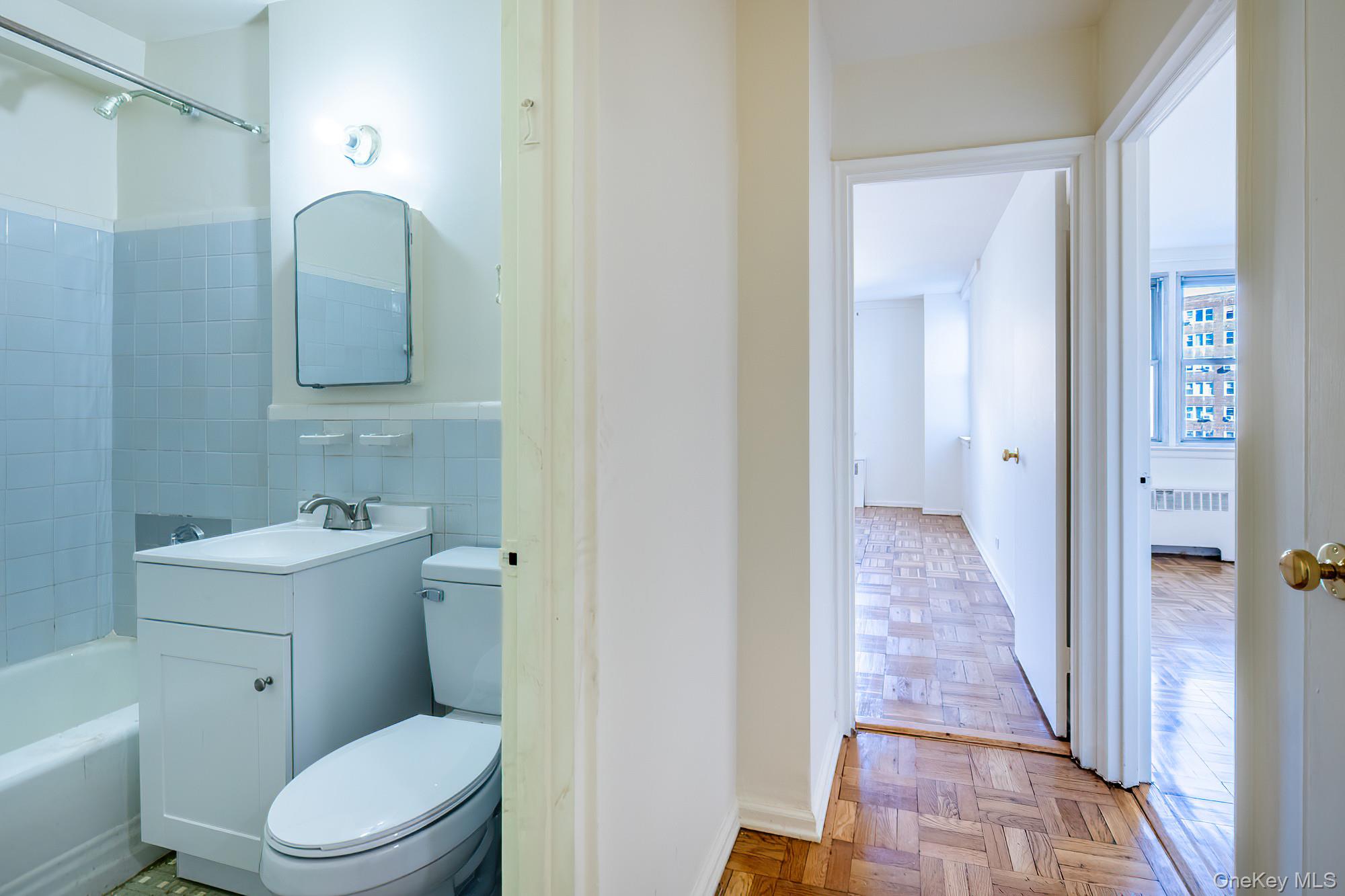 25 Knolls Crescent, Unit 9E Bronx, NY 10463 - Photo 17 of 23 Full bath with tub / shower combination, radiator, vanity, and tile walls