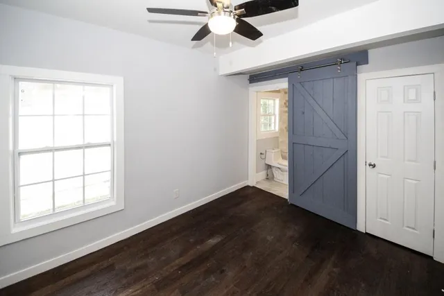 an empty room with wooden floor chandelier fan and windows