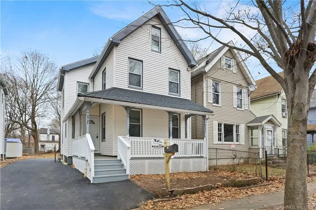 a front view of a house with a yard and large tree