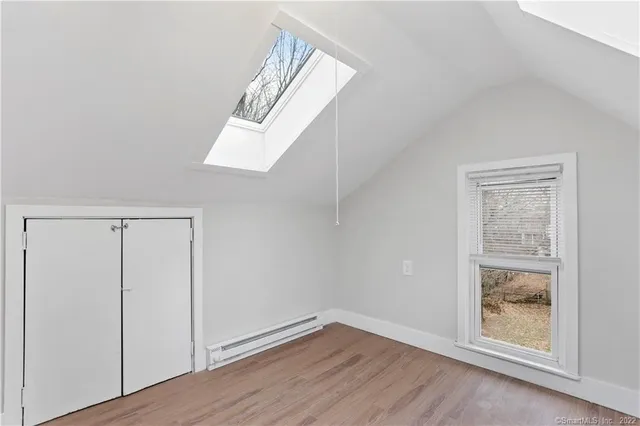 an empty room with wooden floor cabinet and windows