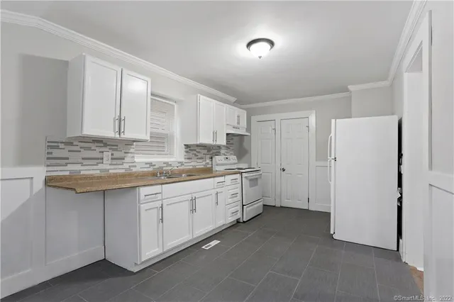 a kitchen with granite countertop white cabinets and white appliances