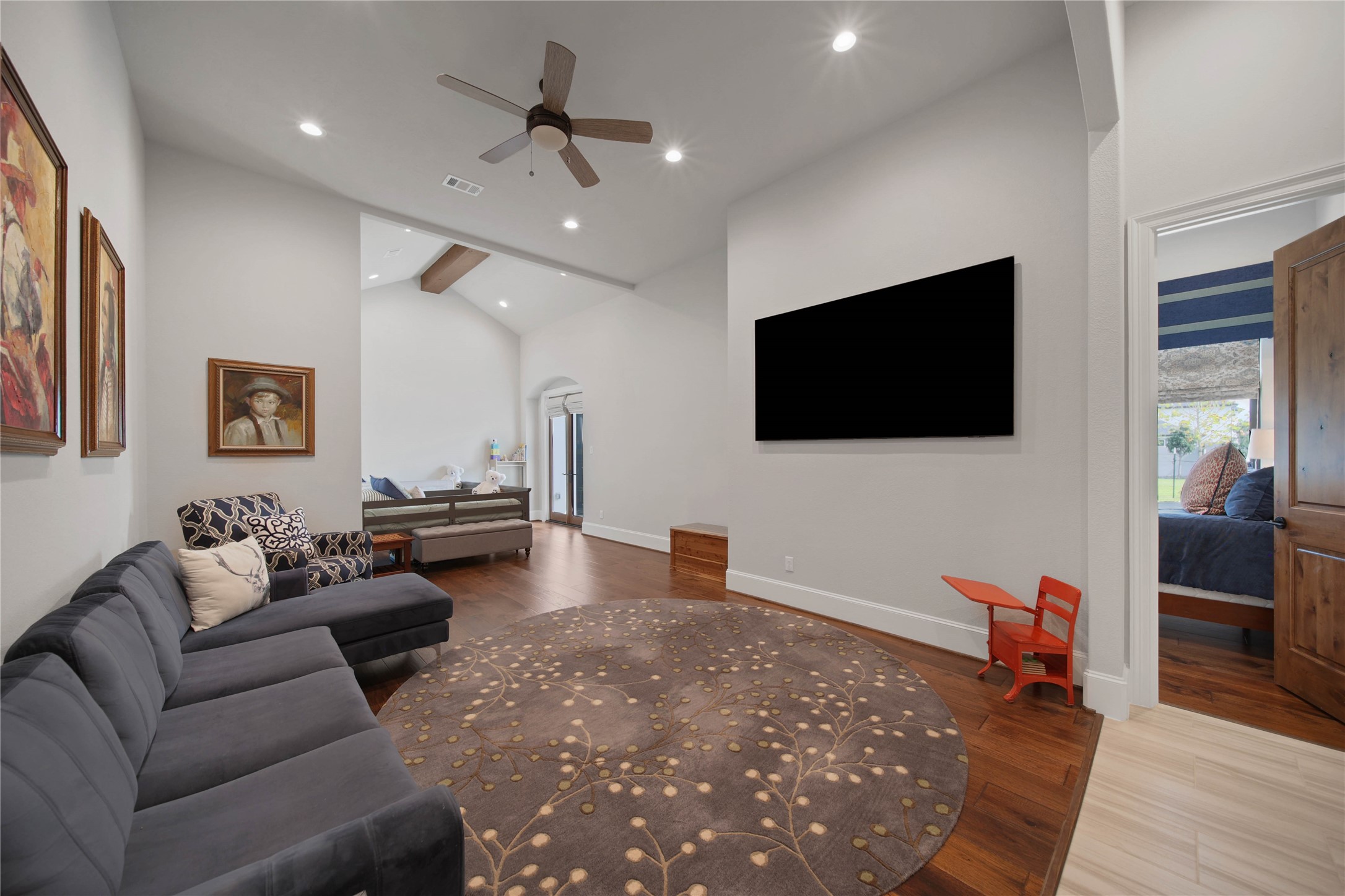 24718 Shadow Pond Spring, TX 77389 - Photo 26 of 49 Spacious living area with high ceilings, modern ceiling fan, and hardwood floors, featuring a comfortable seating arrangement and large wall-mounted TV.