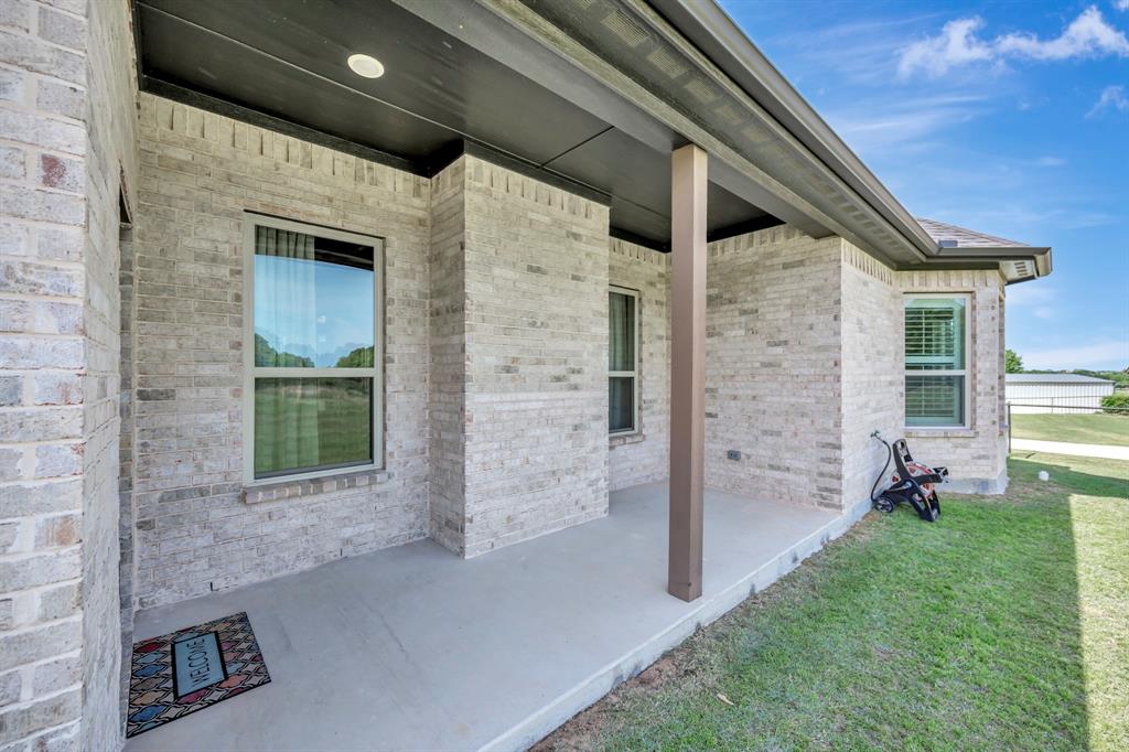 3224 North Cardinal Road Azle, TX 76020 - Photo 31 of 40 Front porch featuring light-colored brick exterior, a supportive column, a concrete slab, and a dark soffit with recessed lighting