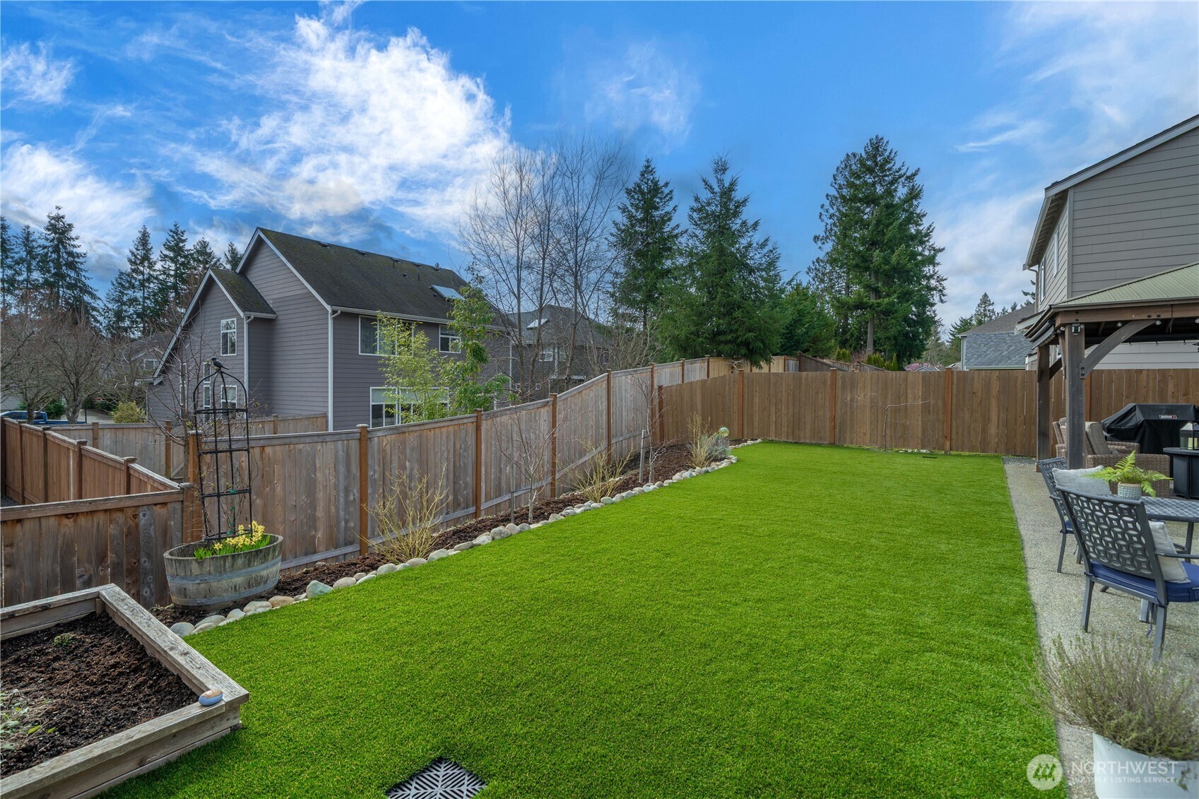 26239 227th Terrace Southeast Maple Valley, WA 98038 - Photo 32 of 37 a view of a backyard with table and chairs and wooden fence