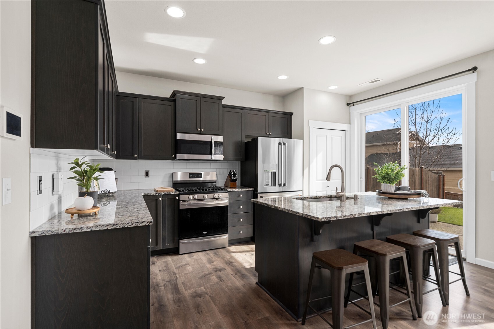 26239 227th Terrace Southeast Maple Valley, WA 98038 - Photo 8 of 37 a kitchen with stainless steel appliances granite countertop a stove a sink dishwasher a microwave oven and a refrigerator with wooden floor