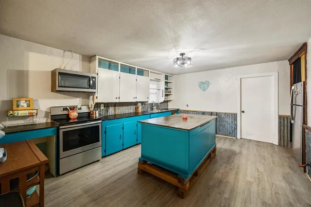 a kitchen with kitchen island granite countertop a sink cabinets and stainless steel appliances