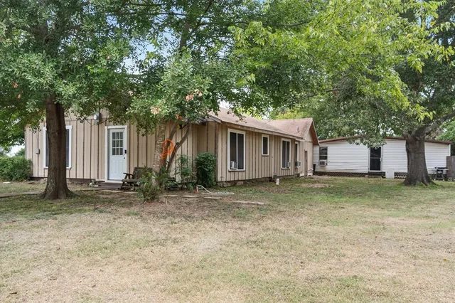 a view of a house with a yard and large tree