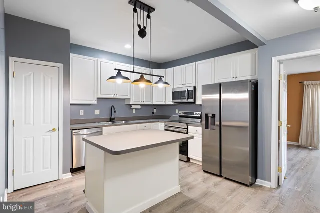 a kitchen with stainless steel appliances granite countertop a refrigerator a sink a stove and white cabinets