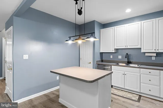 a kitchen with stainless steel appliances a white cabinets and wooden floor