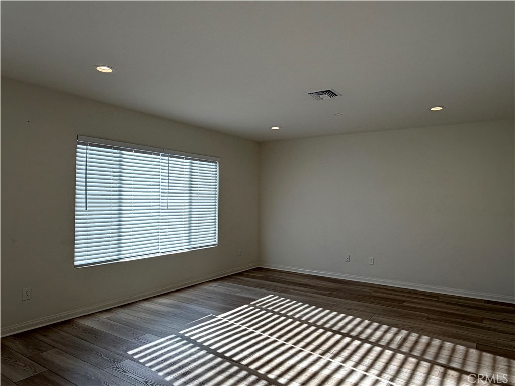 7631 Rubyred Gln Drive Riverside, CA 92507 - Photo 7 of 17 a view of an empty room with wooden floor and a window