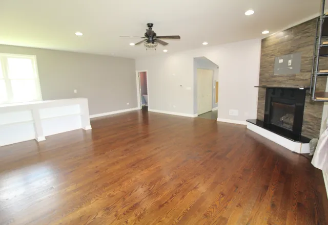 an empty room with wooden floor fireplace and windows