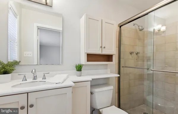 a bathroom with a granite countertop sink a mirror and shower