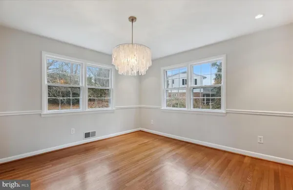 a view of empty room with wooden floor and chandelier