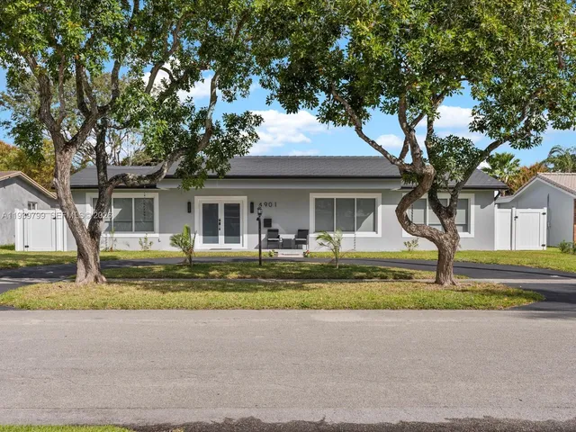 a front view of a house with a garden and trees