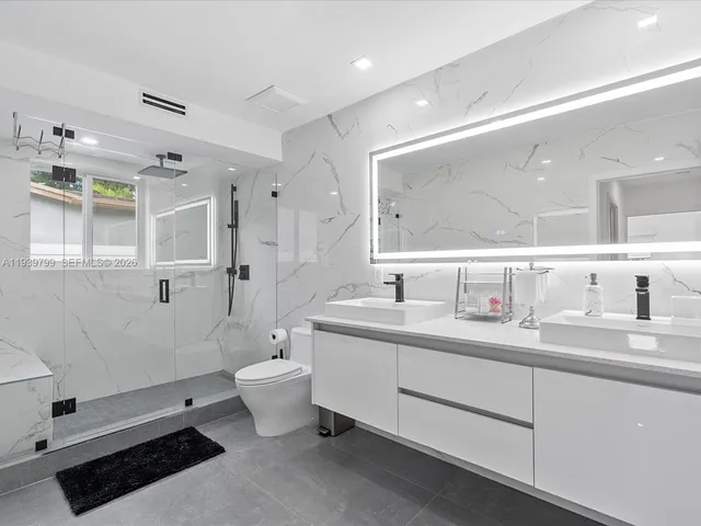 a bathroom with a double vanity sink toilet mirror and bathtub