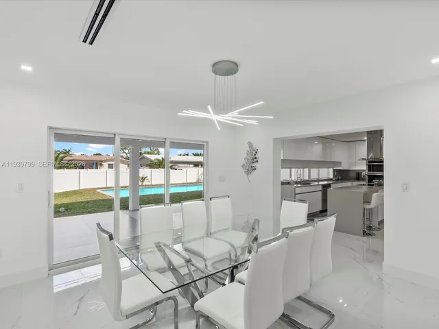 a dining room with furniture a chandelier and kitchen view