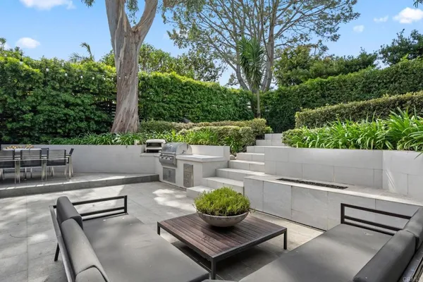 a view of a patio with couches chairs potted plants and a tree