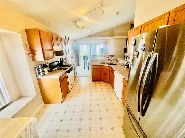 a kitchen with stainless steel appliances a refrigerator a stove a sink a washer dryer and a dining table