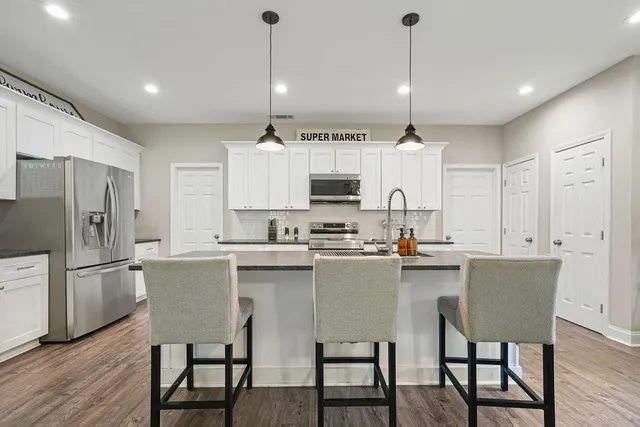 a kitchen with kitchen island a dining table chairs sink and cabinets