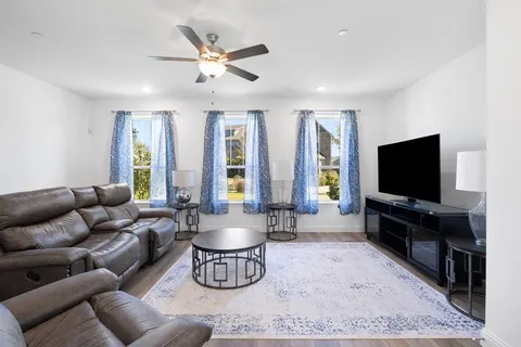 a living room with furniture a ceiling fan and a rug