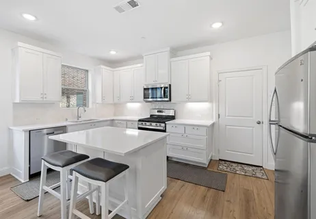 a large white kitchen with a sink and dishwasher a stove top oven with wooden floor
