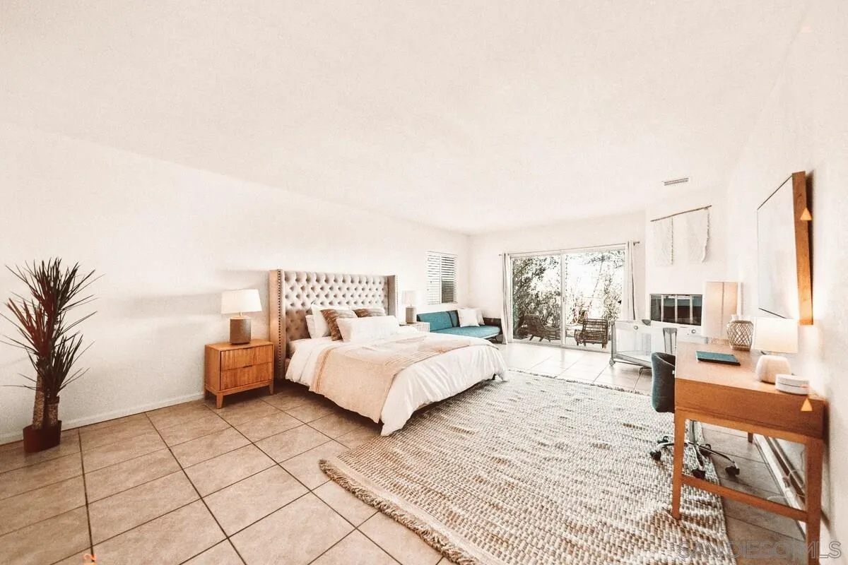 3900 Ave Tortuga Joshua Tree, CA 92252 - Photo 19 of 28 a spacious bedroom with a bed a couch and a potted plant